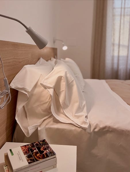 Bedroom with crisp white linen, wooden headboard and reading lights